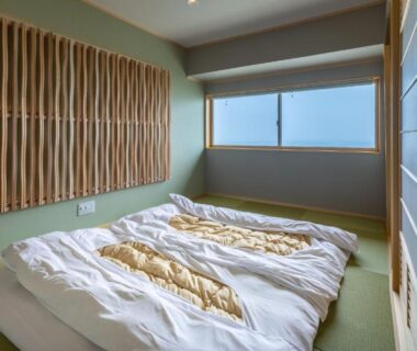 Low futons on tatami floor beside wooden slatted wall in AtamiOnsen Nagahamaen room, Shizuoka Prefecture, Chūbu