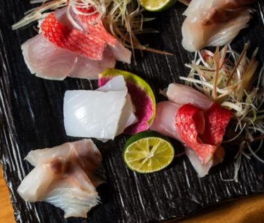 Assorted sashimi with citrus and garnishes on black plate at Atarayo Nishiizu Onsen, Shizuoka, Chūbu Japan