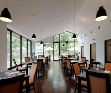 Bright dining room with wooden floors, pendant lights and large windows overlooking garden at Auberge Cosmos Ōita