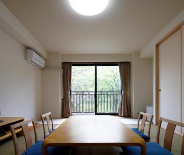 Tatami room with low wooden table, chairs and balcony, Auberge Cosmos in Ōita, Kyushu