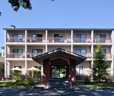 Three-story ryokan facade with balconies at Auberge Cosmos in Oita, Kyushu
