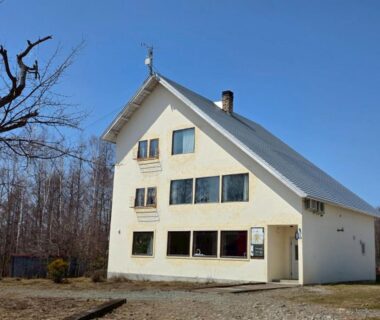 Three-story cream ryokan exterior at Auberge Ninguruforet surrounded by bare trees in Hokkaidō