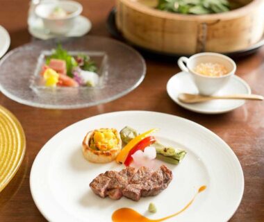 Plated steak course with salad and soup cup on wooden table at Aura Tachibana, Kanagawa