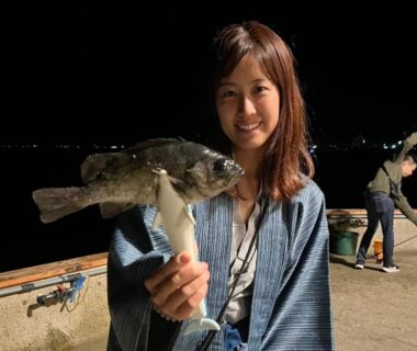 Woman in yukata holding a caught fish on a nighttime dock by Awakan in Hyōgo, Kansai