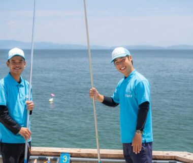 Two staff in blue shirts fishing from wooden pier at Awakan, sea view in Hyōgo, Kansai