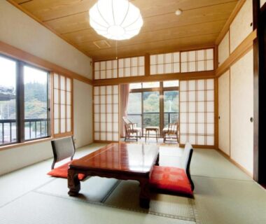 Tatami room with low table, zabuton cushions, shoji screens and hillside view at Ayameya Ryokan in Gunma