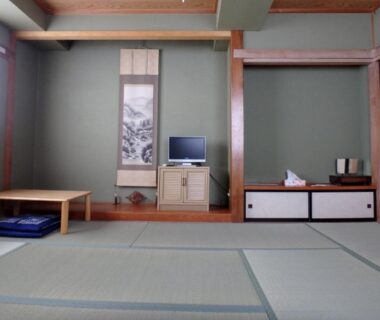 Traditional tatami room with low table, zabuton cushions, hanging scroll and TV at Azuma no Yu in Nagano