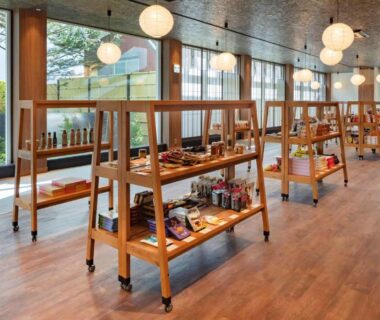 Ryokan lobby with wooden display shelves, products on open racks, large windows and pendant lighting, hardwood floor