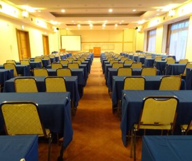 Rows of blue-covered tables and chairs in a conference hall at Azumakan in Fukushima, Tōhoku