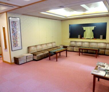 Spacious carpeted seating area with sofas, low tables and kimono wall display at Azumaya Ryokan in Kyoto