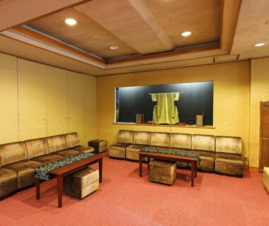 Cozy seating area with upholstered sofas, low wooden tables and noren curtain at Azumaya Ryokan in Kyoto