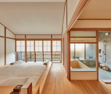 Sunlit Japanese guestroom with low beds, shoji screens and glass-partitioned wooden soaking tub