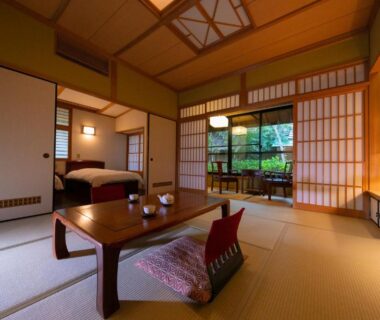 Tatami room with low table, cushion and futon visible through shoji to small garden at Baien Ōita