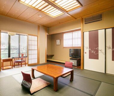 Sunlit tatami room with low wooden table, floor chairs and shoji screens at Baien Ryokan in Ōita