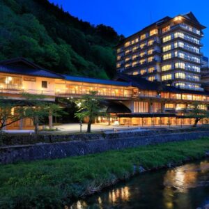 Lit riverside ryokan building by mountain stream Bankokuya Tohoku Yamagata Japan