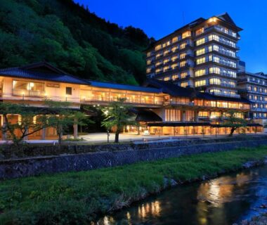 Lit riverside ryokan building by mountain stream Bankokuya Tohoku Yamagata Japan