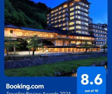 Multi-story ryokan lit at dusk beside a river in Yamagata