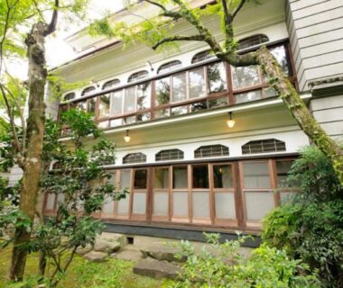 Two-story ryokan exterior with wooden veranda and green garden at Bansuirou Fukuzumi, Kanagawa Japan
