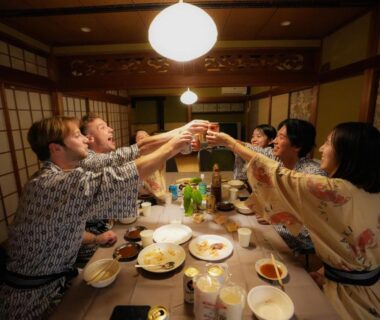 Guests in yukata toasting around a dinner table in tatami room at Base House Kinosaki Hyōgo Kansai