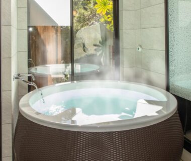 Steaming round indoor soaking tub beside floor-to-ceiling windows overlooking garden at Beautiful Japanese Garden Kagetsu Yamanashi