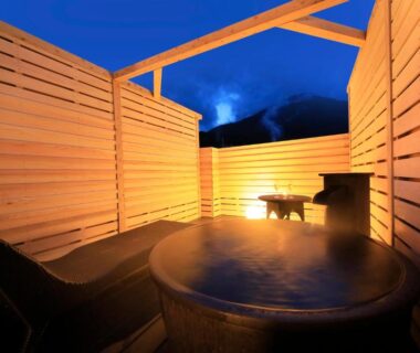 Steaming circular wooden onsen tub on rooftop terrace at Beppu Fuga, Ōita, Kyūshū, Japan