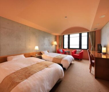 Two beds with concrete accent wall, window seating and desk at Beppu Fuga, Ōita, Kyushu Japan