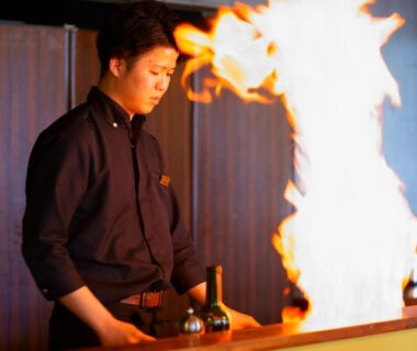 Chef with dramatic flame over wooden counter at Beppu Fuga in Ōita, Kyūshū