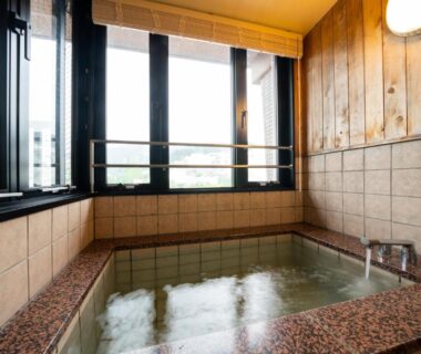 Tiled indoor onsen bath with wooden paneling at Beppu Kannawa Onsen Oniyama Hotel in Ōita, Kyūshū