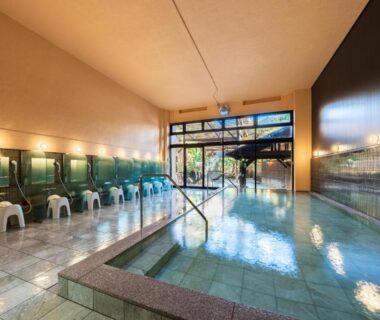 Tiled indoor onsen with stools and shower stations, glass doors to exterior at Beppu Kannawa Onsen Oniyama Hotel, Oita