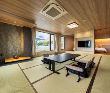 Spacious tatami room with low table, floor chairs and garden-facing windows in Beppu Kannawa, Ōita