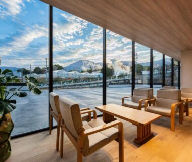 Seated lounge with floor-to-ceiling windows overlooking river and hills at Beppu Kannawa Onsen Oniyama Hotel, Ōita