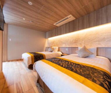 Contemporary twin bedroom with wooden ceiling, warm wall lighting and twin beds at Beppu Kannawa Onsen, Oita