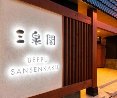 Illuminated wooden entrance sign and doorway of BeppuOnsen Hotel Sansenkaku in Ōita with warm lighting
