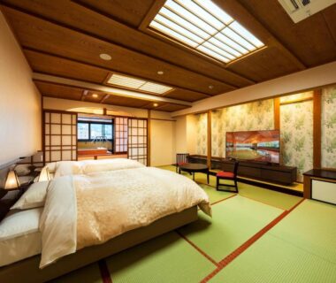 Tatami room featuring two beds, shoji screens, low table, and warm lighting at BeppuOnsen Hotel Sansenkaku in Ōita