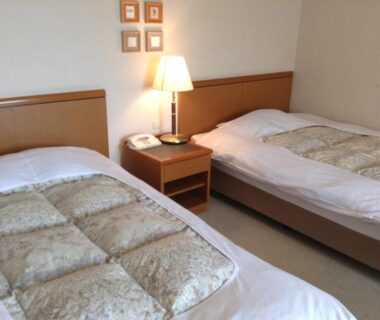 Two single beds with bedside lamp and framed art in Bergtour Marukita room, Nagano, Chūbu, Japan