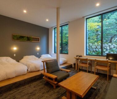 Twin room with low beds, wooden table and garden view at Bessho Onsen Midoriya in Nagano