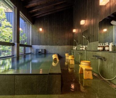 Indoor tiled onsen with wooden stools and shower stations at Bessho Onsen Midoriya, Nagano, Chūbu, Japan
