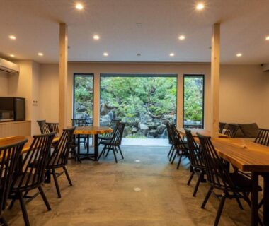 Communal dining area with wooden tables and garden view at Bessho Onsen Midoriya in Chūbu, Nagano
