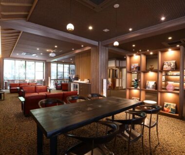 Warm wood lounge with tables, bookshelf and seating at Besshoonsen Nanjyo Ryokan Nagano