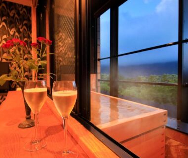 Wooden soaking tub by window with two glasses at Bettei Koyoi in Kanagawa