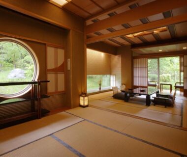 Traditional tatami room with low table, circular window and garden view at Bettei Senjyuan in Gunma