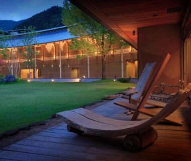 Wooden lounge chairs on a deck overlooking a courtyard lawn at Bettei Senjyuan in Gunma Kanto