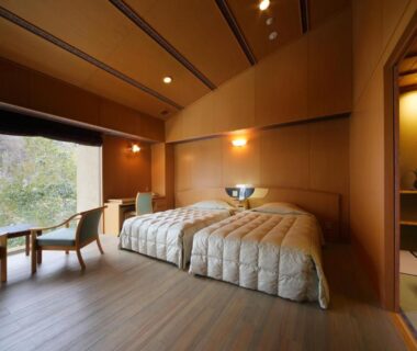 Wooden twin room with low chairs and large window overlooking a wooded garden