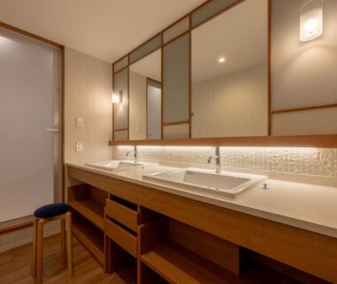 Double sink vanity with wooden counter, mirrors and stool at Biei Shirogane Onsen AONOBI YUYU Hokkaidō