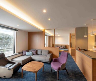 Modern lounge with sofa and armchairs at AONOBI YUYU in Hokkaidō with window view of wooded hillside