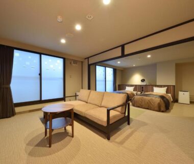 Spacious room with sofa, low table and bed at Biei Shirogane Onsen AONOBI YUYU, Hokkaidō, Japan