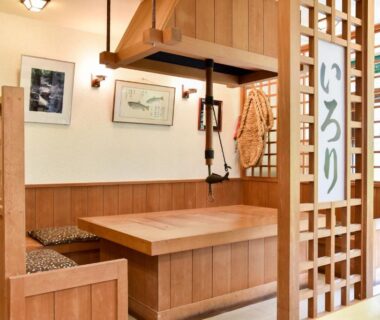 Wooden irori dining alcove with low table, woven cushions and shoji-style partition at Bijintei, Wakayama