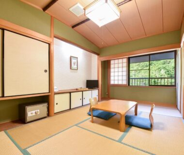 Tatami room with low table, zabuton cushions and shoji window overlooking greenery at Bijintei, Wakayama