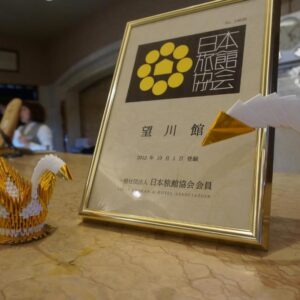 Framed certificate and origami cranes on Bosenkan reception counter in Gifu, Chūbu