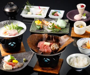 Assorted traditional Japanese multi-course meal with grilled meat, rice, soup and small seasonal side dishes on lacquerware